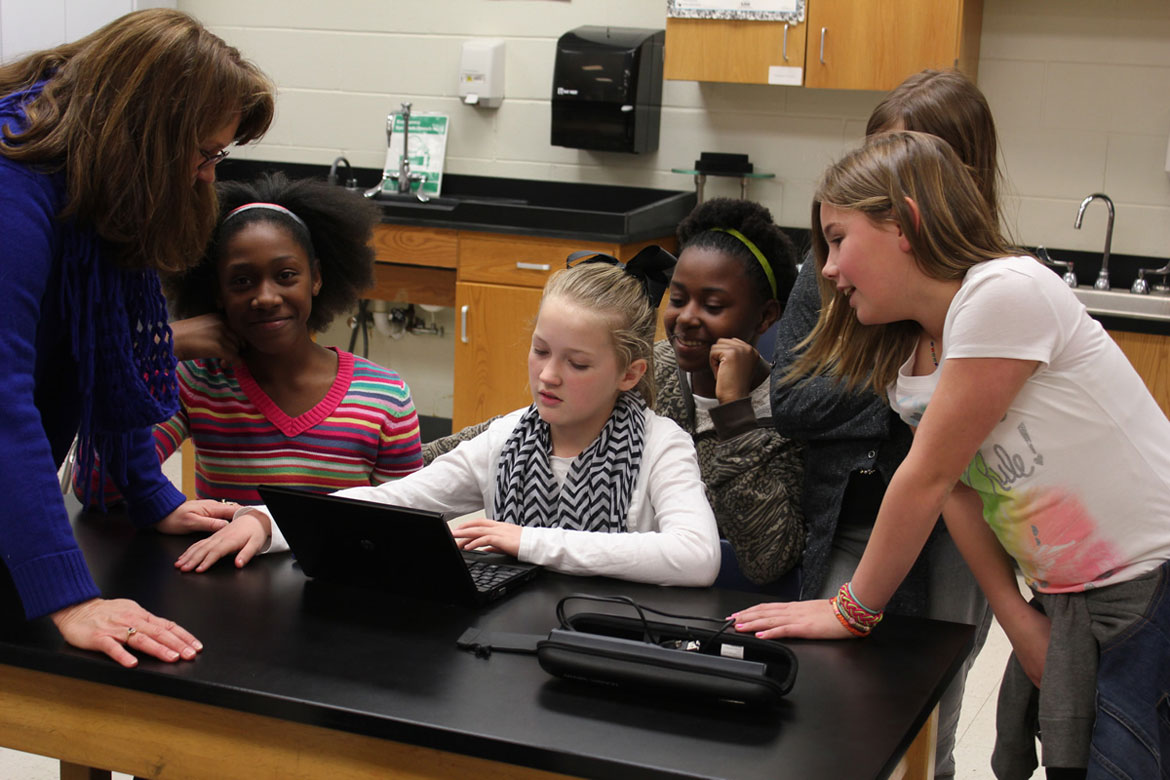 students and teacher working at computer