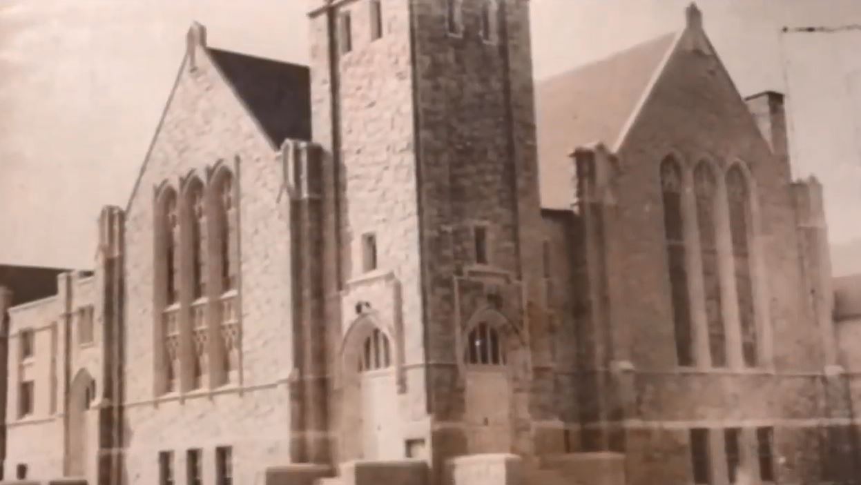 A vintage photo of a gothic-looking church with a tower and two gabled ends. 