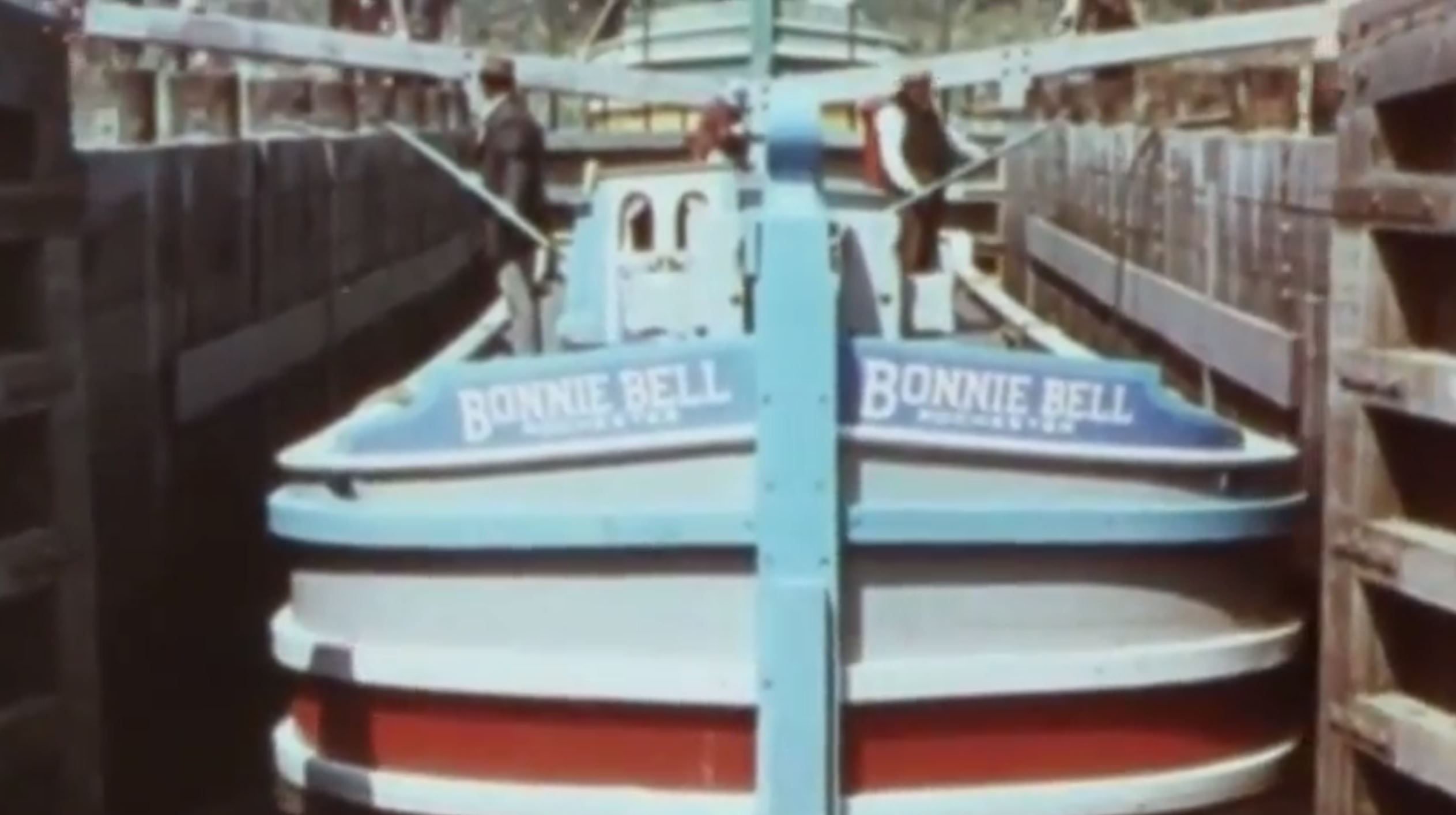 A vintage photo of a blue boat going through a small canal pass. 