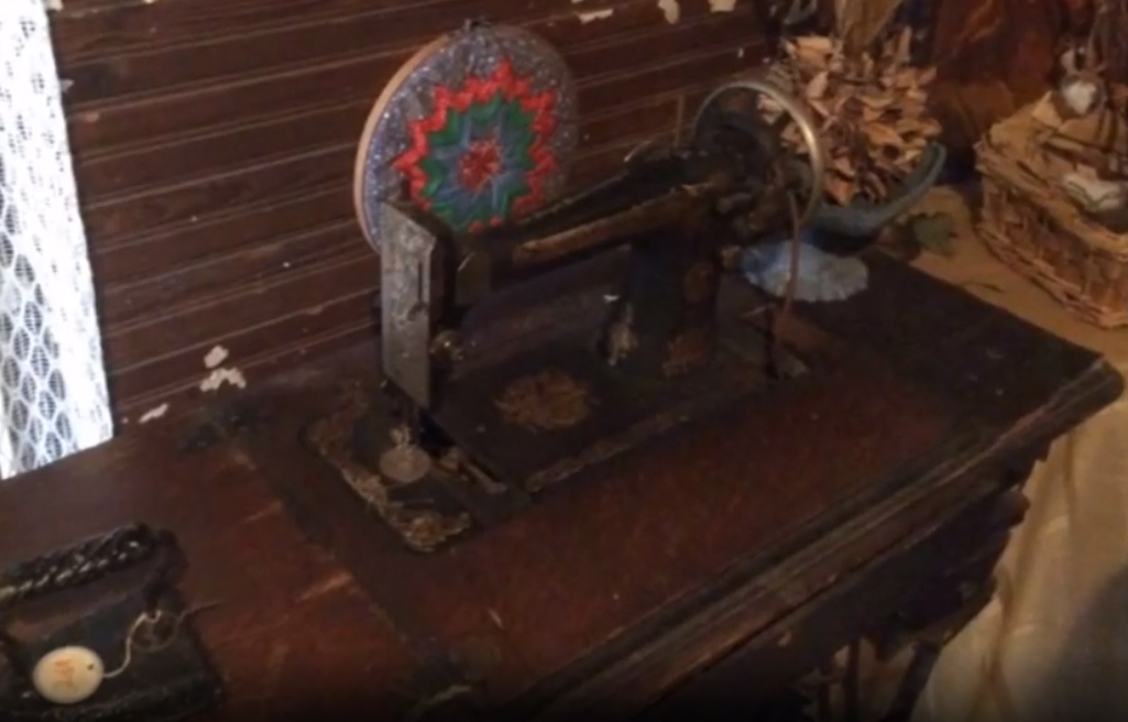 View of a vintage sewing machine in a log-cabin setting.