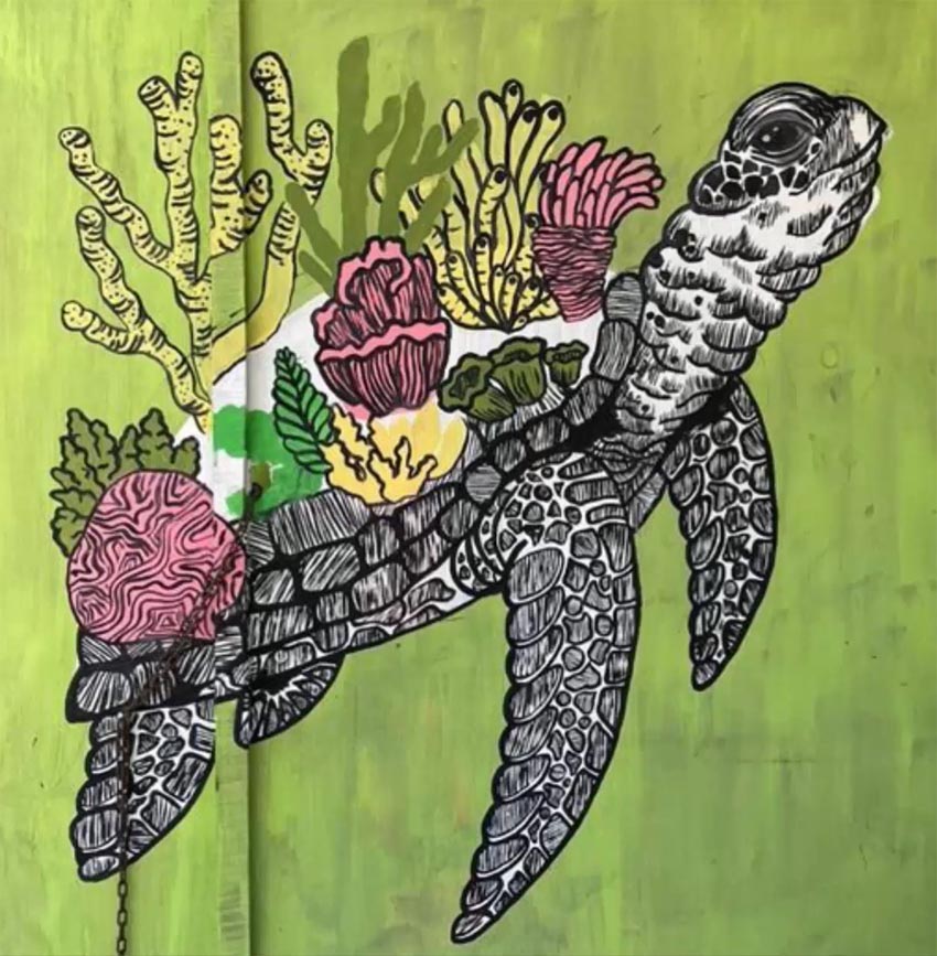 A painting of a sea turtle with corals on its back, painted on a green wall. 