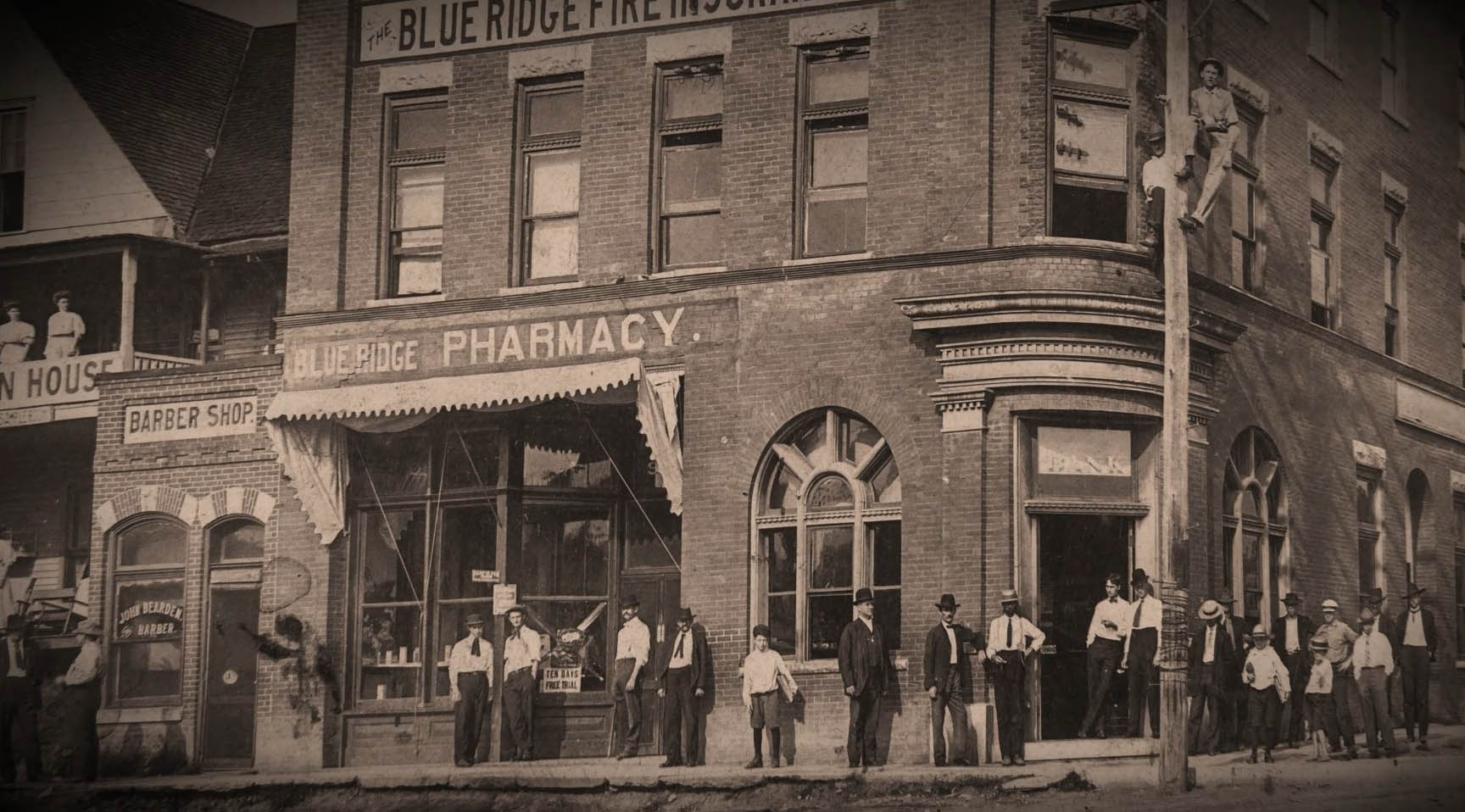 Vintage photo of a pharmacy in the early 20th as people stand on the corner and wait outside.
