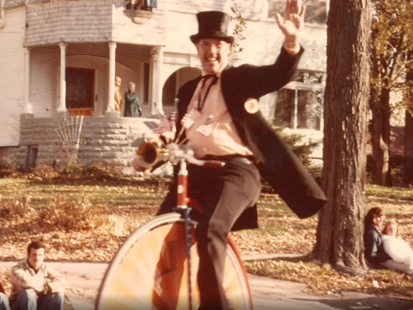 A man in a top hat rides a unicycle in a vintage photo.