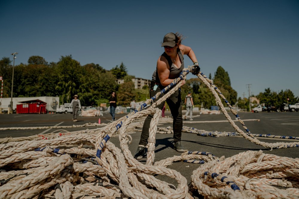 A woman hauls lengths of recycled rope in a parking lot.