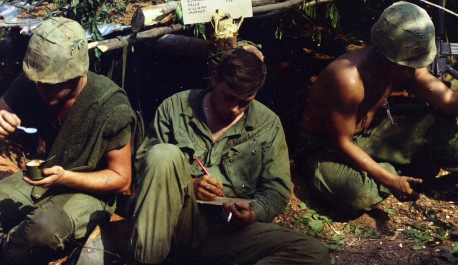 Vintage photo of soldiers sitting outside writing letters in the 1960s or early 1970s.
