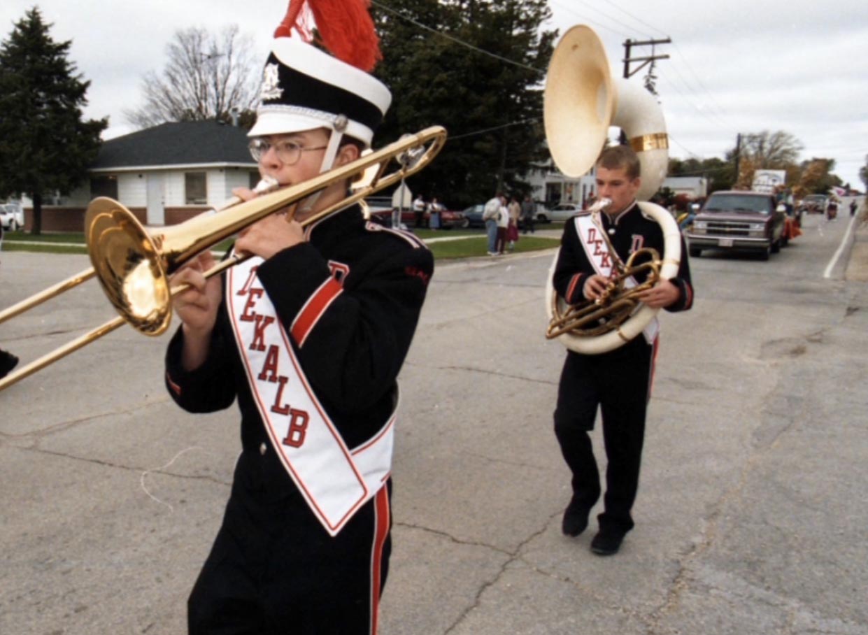 Two boys play a trumpet and tuba in a small town parade.