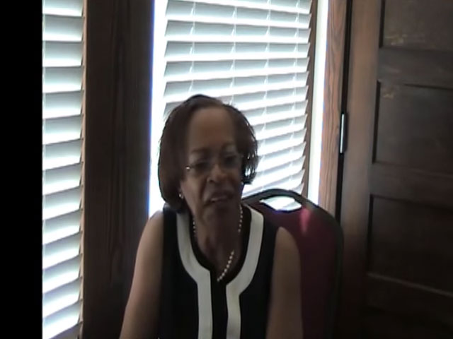 Screenshot from video documentary on Galesville Rosenwald School, showing an African American woman wearing glasses and a black-and-white top.