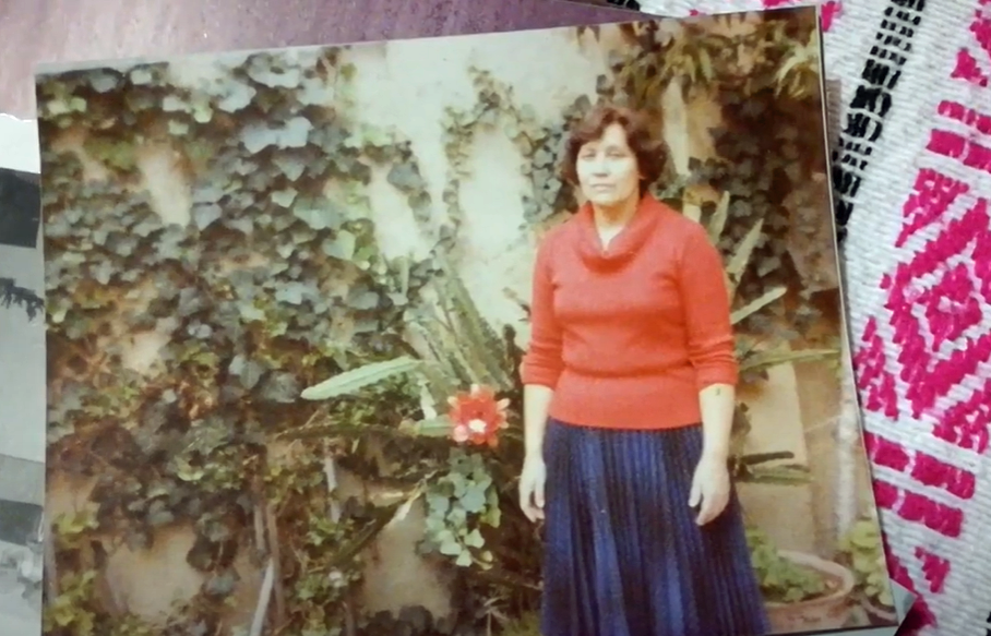 A woman in a red sweater and denim skirt appears in a vintage photograph.