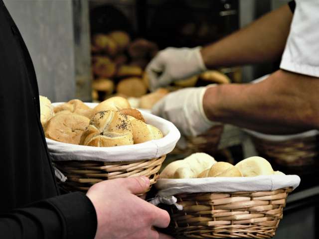 A man holds two baskets full of fresh-baked rolls. Pexels stock photo