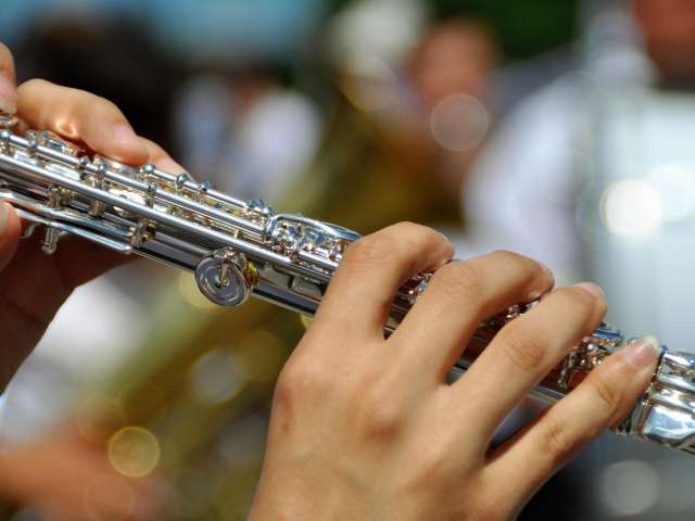 A woman holds a flute in a band. Pexels stock photo.