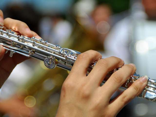 A woman holds a flute in a band. Pexels stock photo. 