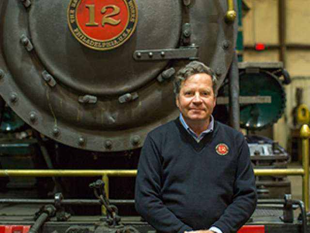 Christopher Robbins poses in front of a steam engine. 