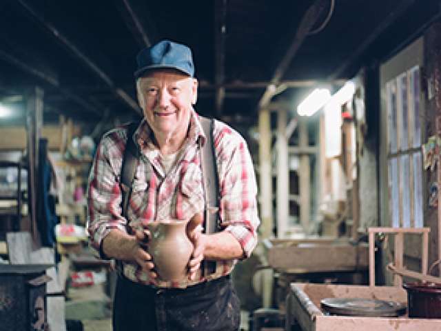 Glenn Bolick in his pottery, holding a pot. 
