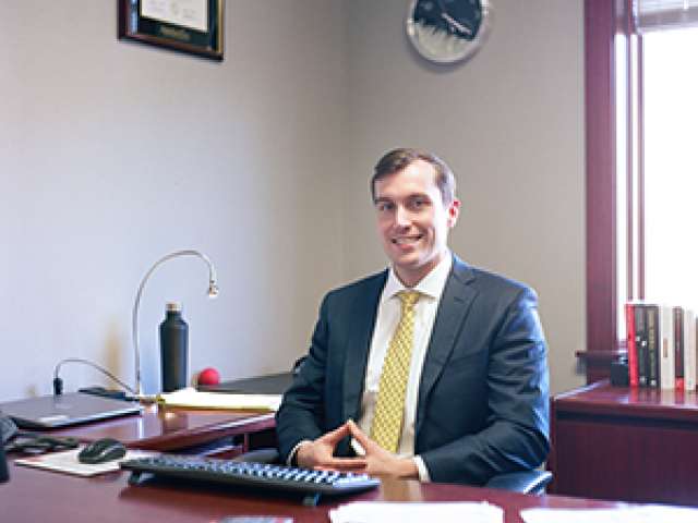 Keith sits in his office, wearing a suit. Courtesy Blowing Rock Art and History Museum