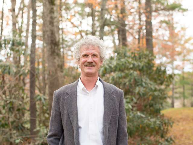 Kinney, in a gray jacket, poses outside. 