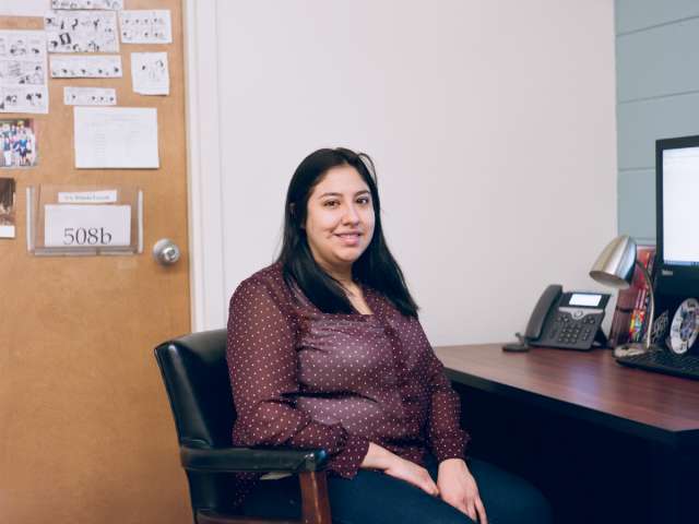 Navila Castro sits in her office at a desk.