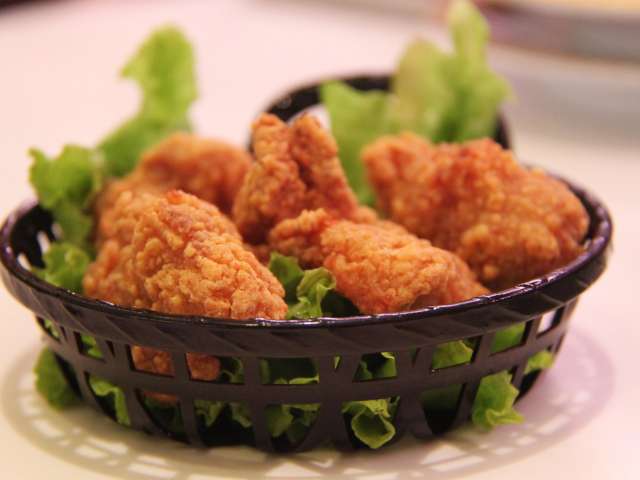 Several pieces of crispy fried chicken in a plastic basket on a bed of lettuce. Pexels stock photo