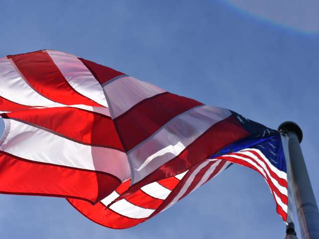 An American flag waves in the wind, as seen from below. Pexels stock photo