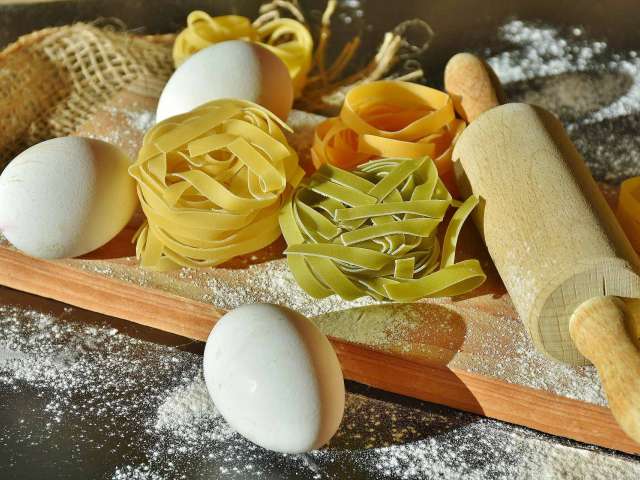 A wooden cutting board with dried noodles and eggs on it. Pixabay