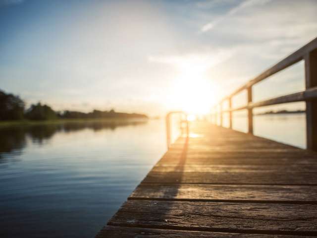 A dock leads out to a placid lake. Pexels