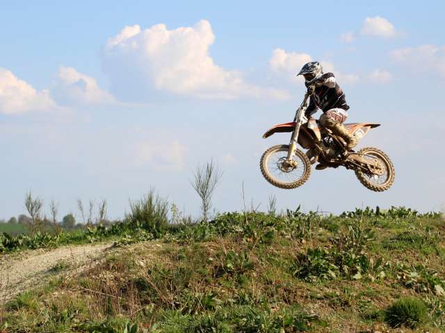 A person races on a motor bike over a hill. Pexels photo.