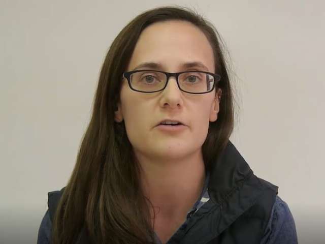 Emily, wearing glasses, looks at the camera.