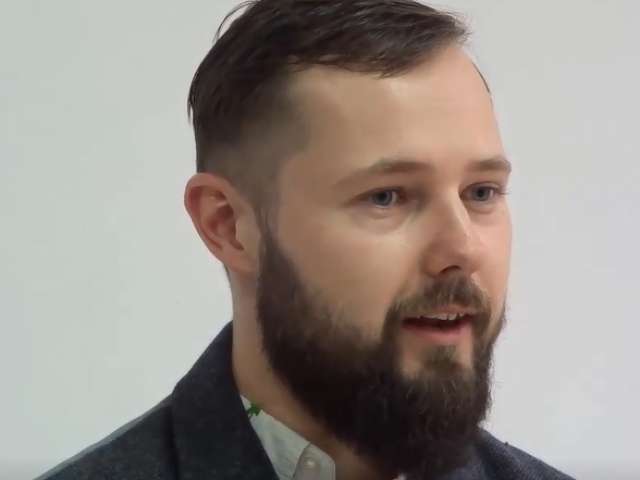 Áki looks to the side as he speaks to an interviewer.