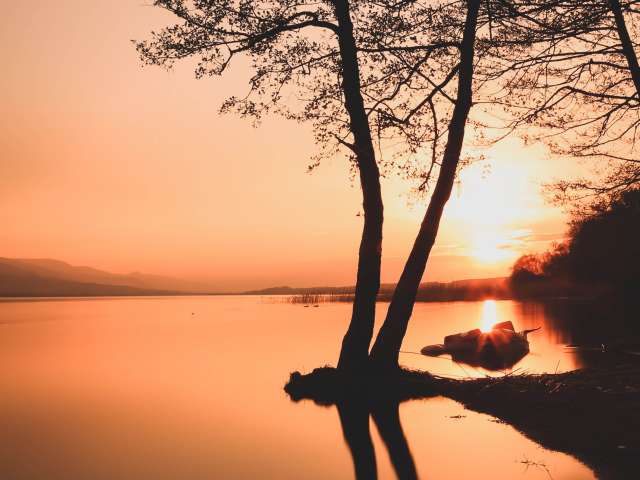 A beautiful sunset as seen across a serene, glassy lake. 