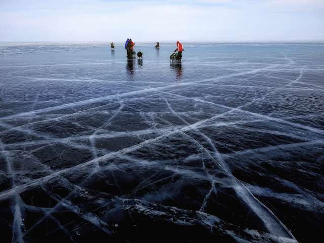 People take sled out onto a icy lake in winter. 