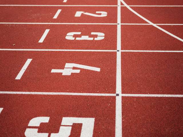 A close up of a track-and-field track with the numbers in white letters on the lanes. 