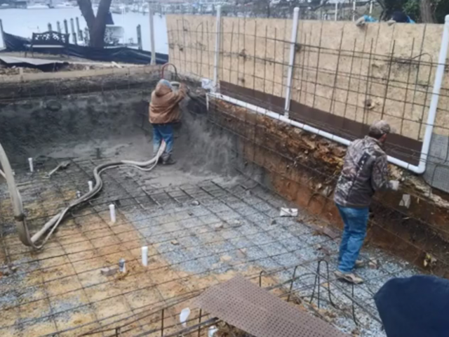 Two men set up a silt fence around an area where they are building a pool. 