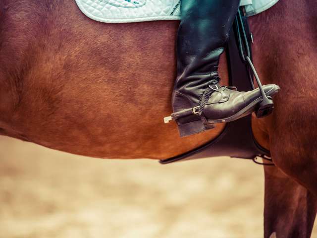 A pair of worn cowboy boots nestled into horse stirrups.