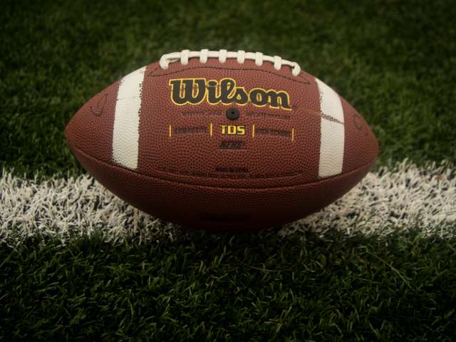 A football rests on a goal line on a football field. 