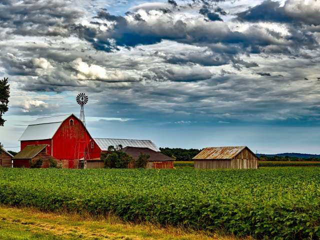 A picturesque red barn beside a corn field. 