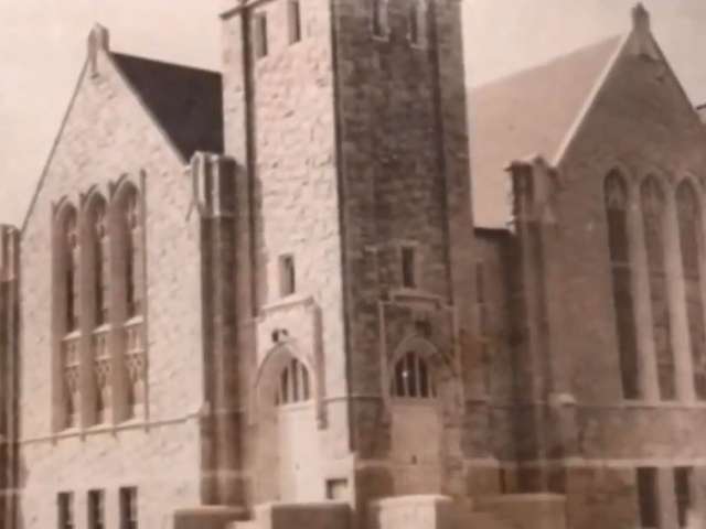 A vintage photo of a gothic-looking church with a tower and two gabled ends. 