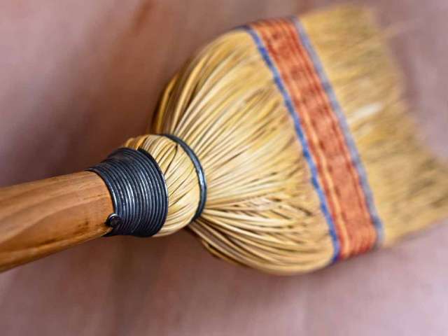 The end of a natural fiber broom as it sweeps the floor. 