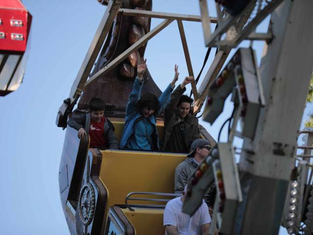 Thrill seekers put their hands in the air as they ride a swinging amusement park ride. 