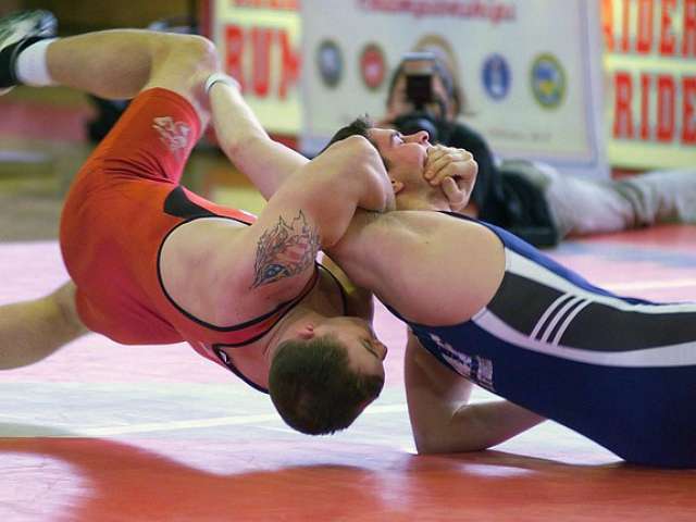 Two young men wrestle in a collegiate match. 