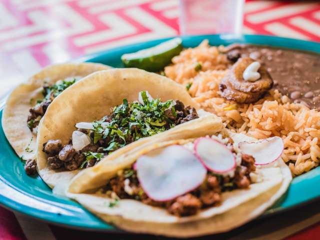 A delicious plate of Mexican food with beans, rice, and tortillas. 