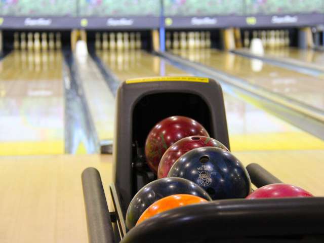 Colorful bowling balls lined up at a bowling alley.