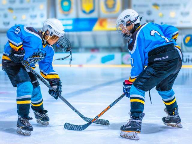 Two boys in ice hockey uniforms play on the ice.
