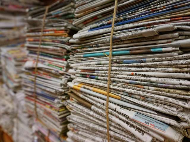 Several stacked bundles of newspapers, tied with brown string. 