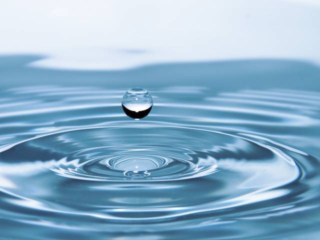 A close-up view of a droplet of water as it splashes into a pool. 