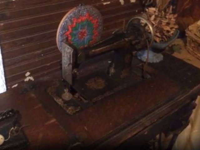 View of a vintage sewing machine in a log-cabin setting.