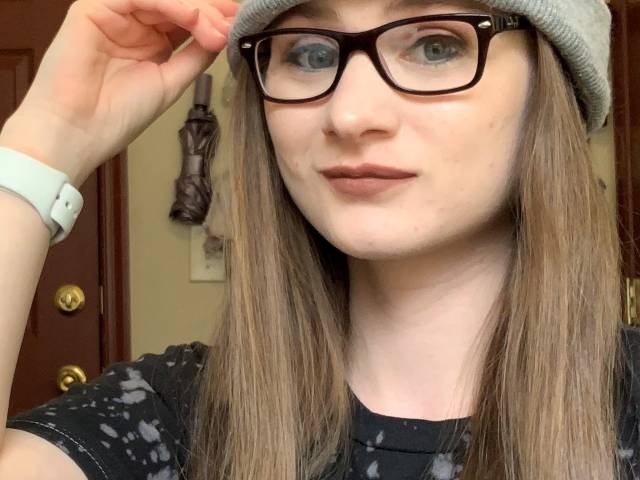 Amber has long brown hair, eye glasses, and a gray knit cap.