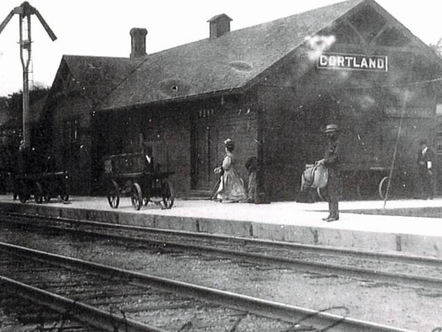 A view of vintage railroad depot in Illinois shows people on the platform.