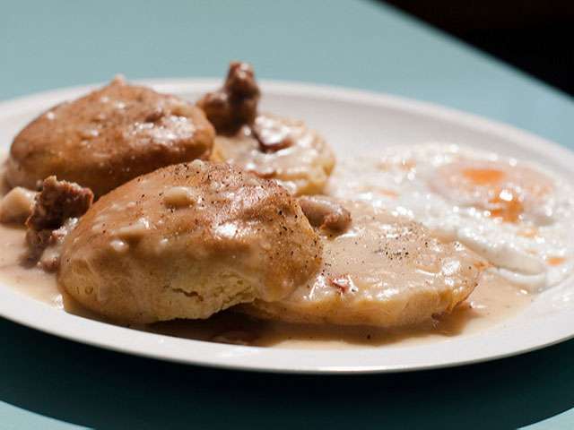 A plate of biscuits, smothered with gravy.