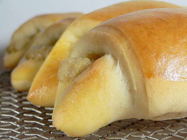 A close-up view of fresh baked rolls on a metal sheet. 