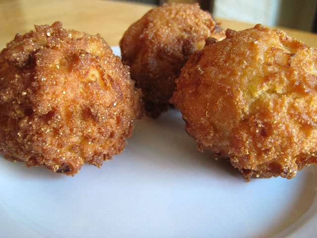 Deep-fried hush puppies sit on a plate. 