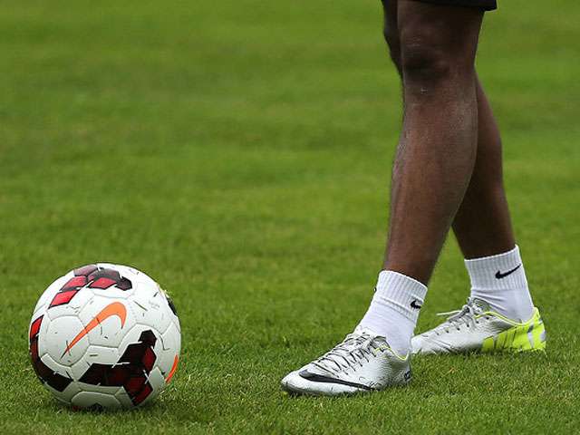 A detail of a man's legs as he approaches a soccer ball. 